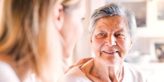 Femme âgée souriante écoutant une femme plus jeune dans un moment complice.