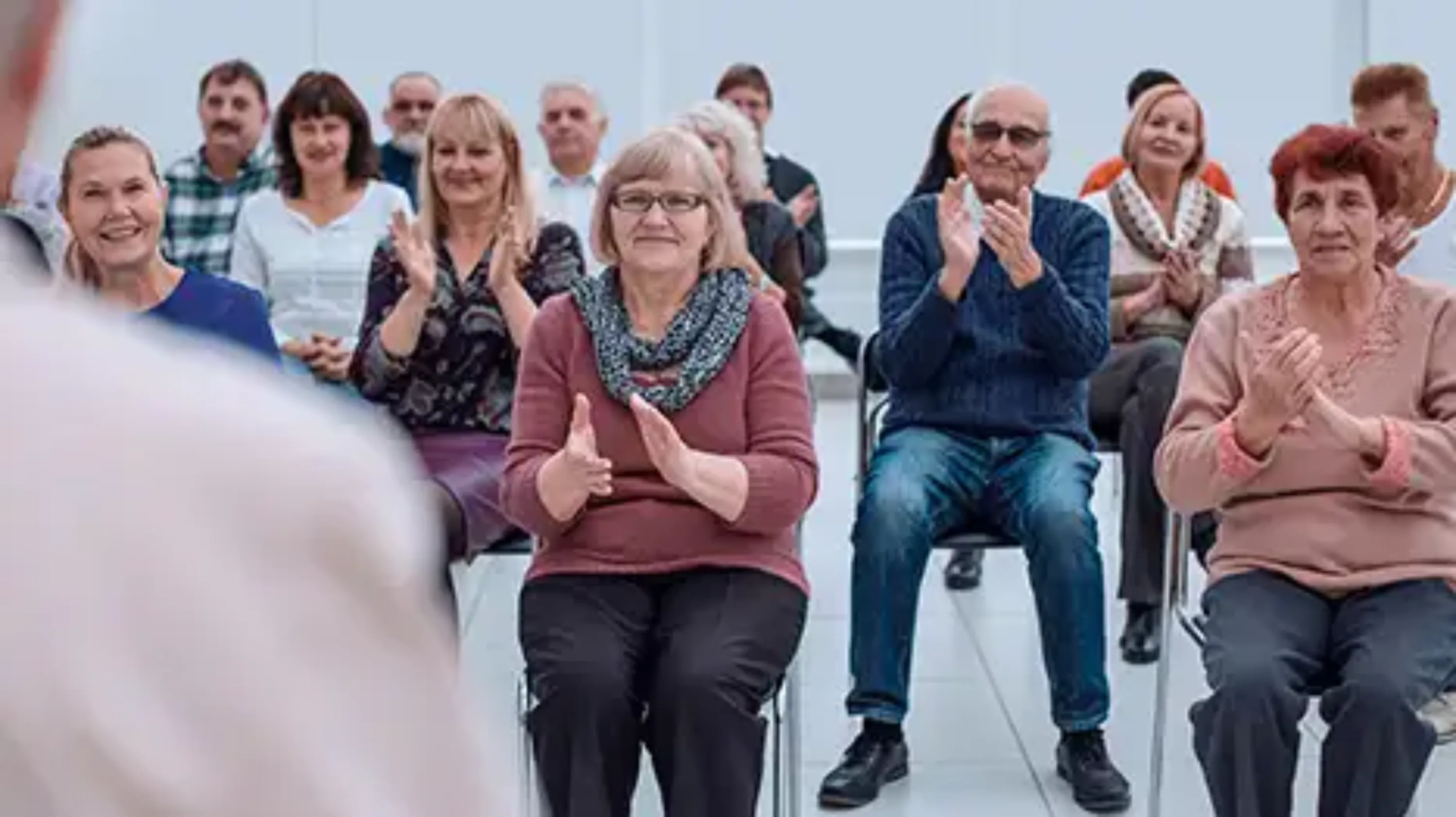 personnes âgées qui applaudissent un intervenant lors d'une conférence