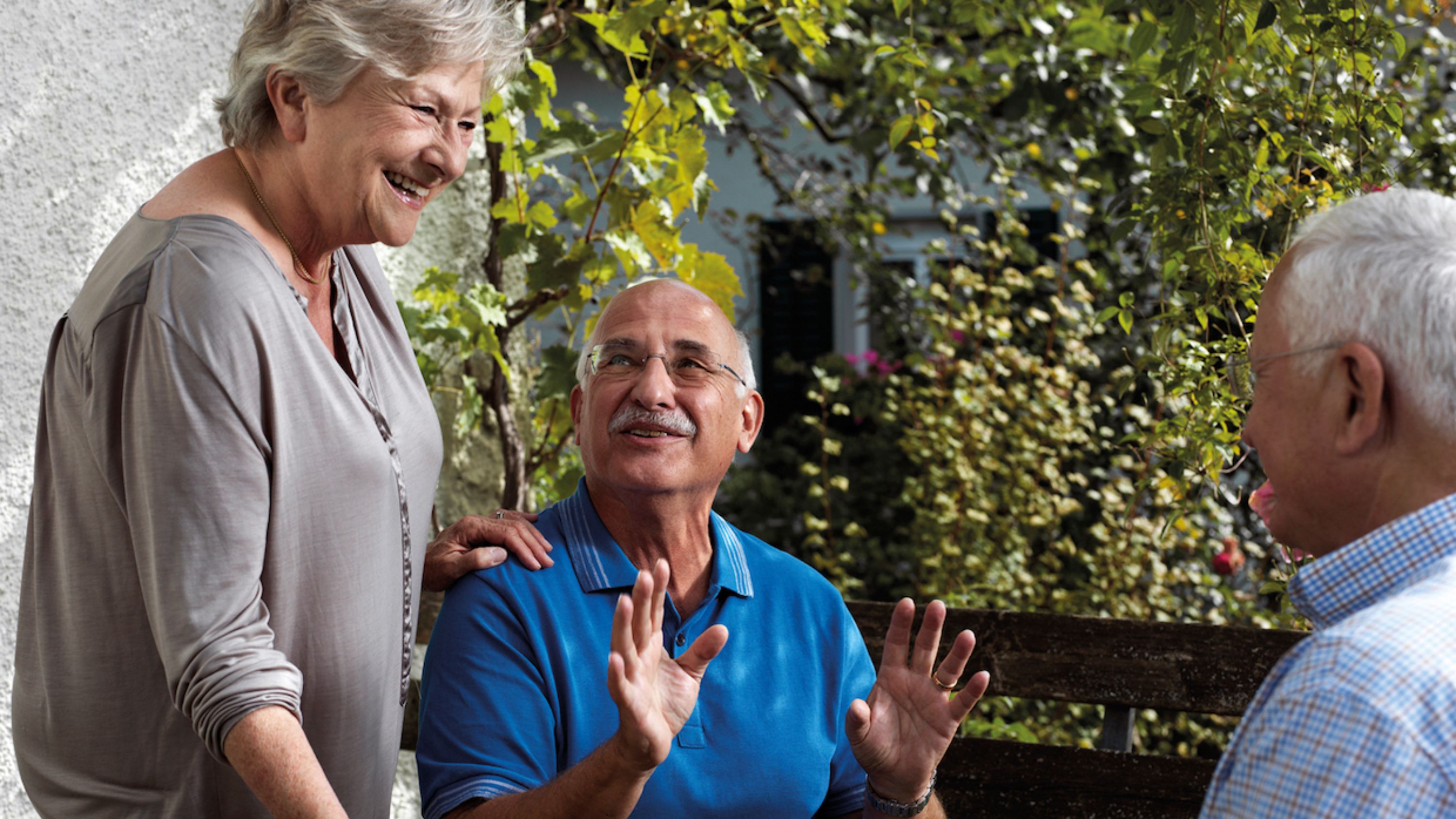 3 personnes âgées qui discutent ensemble en extérieur 